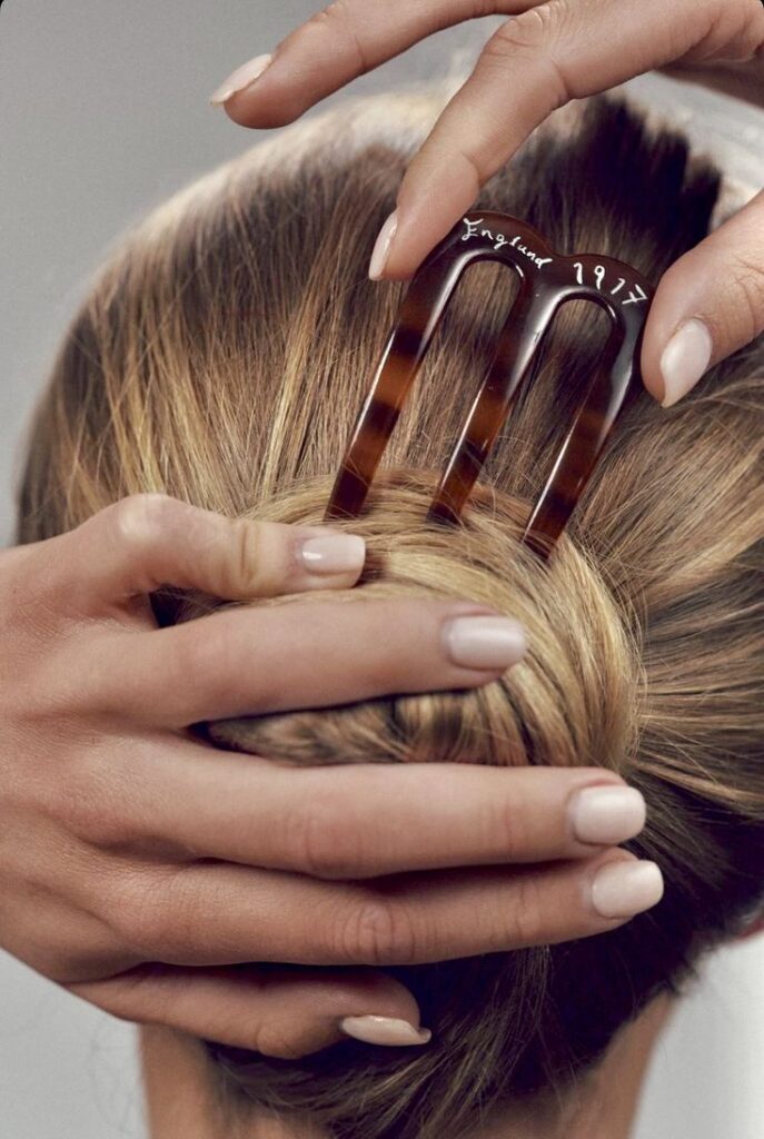 Elegant hair twist secured with a vintage tortoiseshell hairpin, close-up of hands styling.