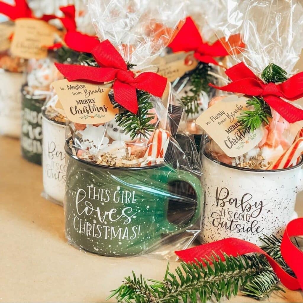 Festive holiday gift mugs with red ribbons and greenery, perfect for Christmas presents and seasonal decorations.