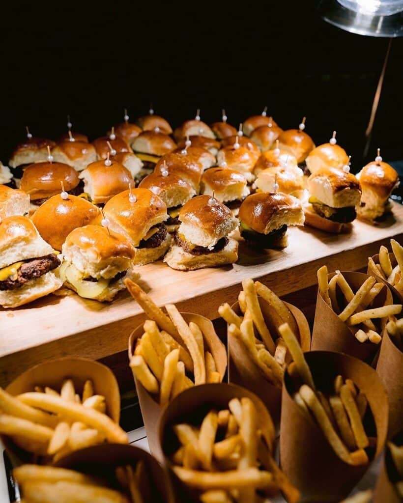 Mini sliders and fries served on a wooden board, perfect for events and parties. Delicious snack idea.