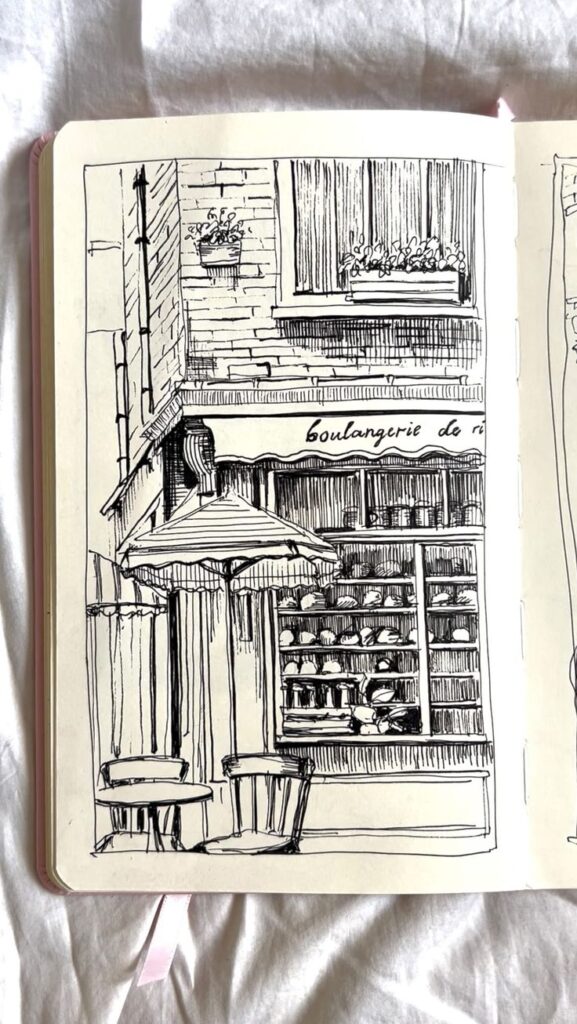 d5147c7a-3fdd-47d9-8948-10d46162059a Sketch of a quaint French bakery facade with window display and outdoor seating. | Sky Rye Design Sketch of a quaint French bakery facade with window display and outdoor seating.