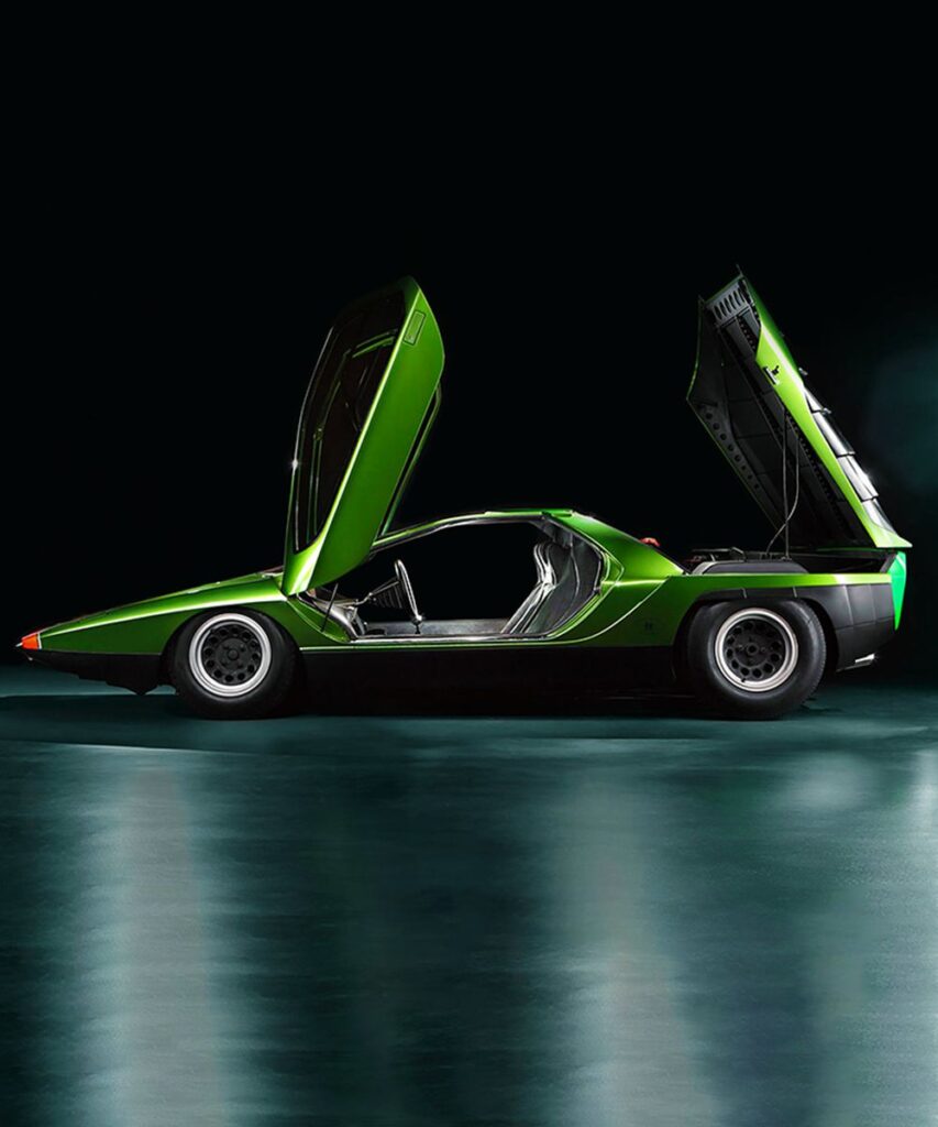 Futuristic green car with gullwing doors open, side view on a reflective surface.