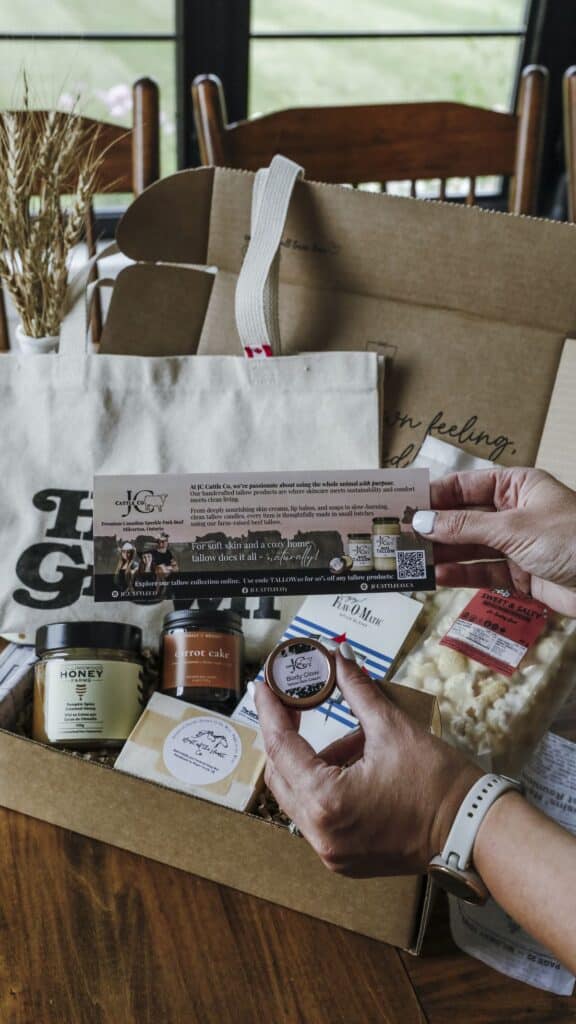 d8ab53a611c37235ec87100914a7496c Gift box with skincare products, honey, and snacks on a wooden table, hands holding a pamphlet and balm. | Sky Rye Design Gift box with skincare products, honey, and snacks on a wooden table, hands holding a pamphlet and balm.