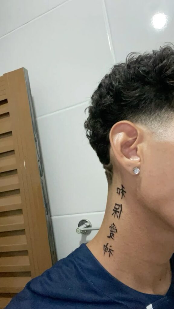 Close-up of a neck tattoo with Chinese characters, short curly hair, and a diamond stud earring.