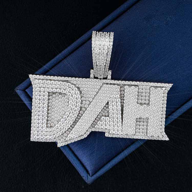 Diamond-encrusted DAH pendant on blue background, showcasing sparkling jewelry craftsmanship.
