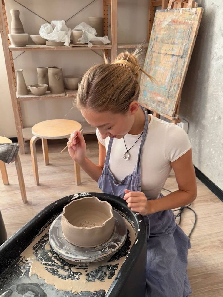 Young woman crafting pottery on a wheel in a cozy studio.
