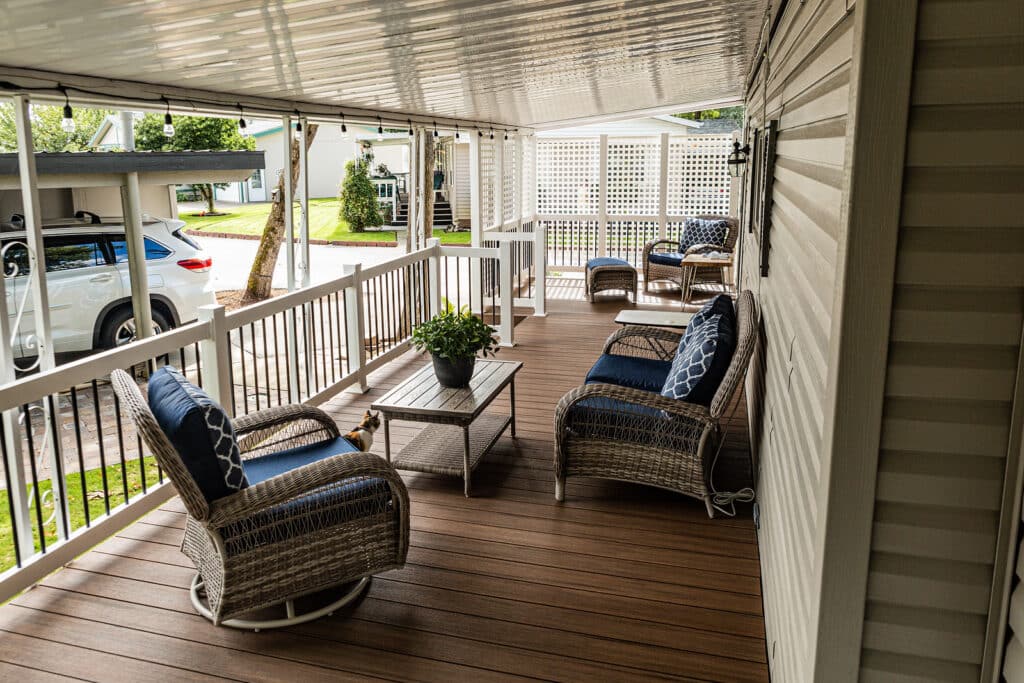 deck-installation-near-me Covered porch with wicker furniture, cushions, and potted plant, overlooking parked car and green lawn. Cozy outdoor space. | Sky Rye Design Covered porch with wicker furniture, cushions, and potted plant, overlooking parked car and green lawn. Cozy outdoor space.