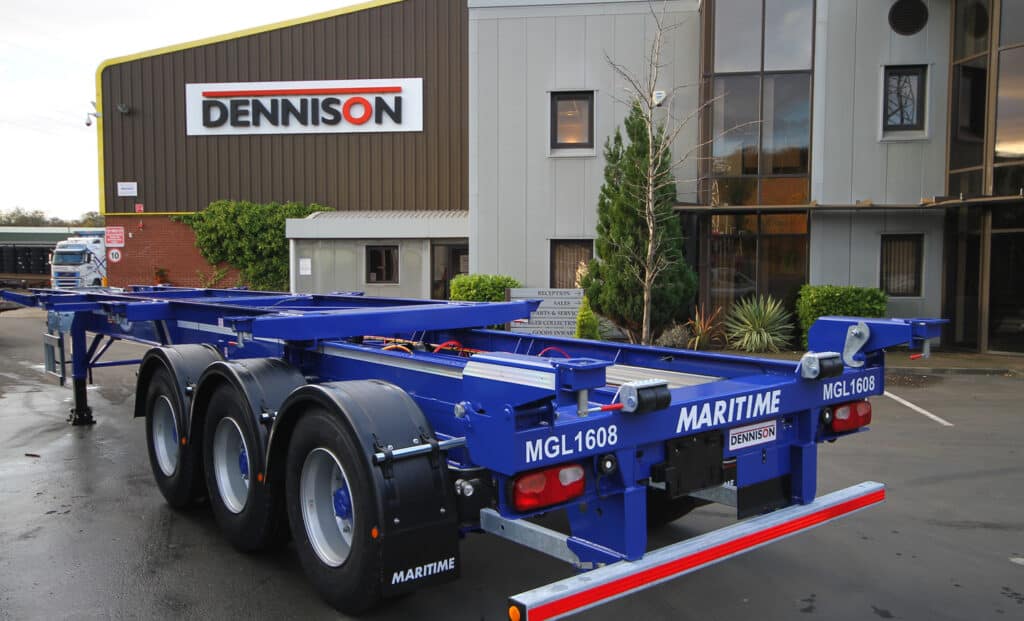 Blue Dennison trailer parked outside industrial building with Dennison signage.