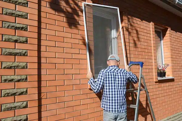 depositphotos_311525028-stock-photo-handyman-installing-mosquito-net-screen Man in plaid shirt installing window screen on brick house with ladder. | Sky Rye Design Man in plaid shirt installing window screen on brick house with ladder.