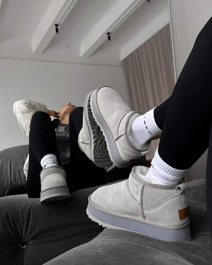 Cozy gray winter boots and black leggings reflected in mirror, styled on plush gray couch.