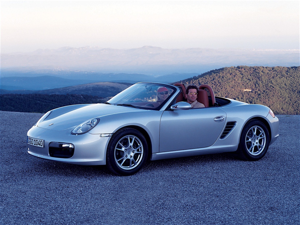 image Silver Porsche Boxster convertible with two passengers parked on scenic mountain overlook at dusk | Sky Rye Design Silver Porsche Boxster convertible with two passengers parked on scenic mountain overlook at dusk