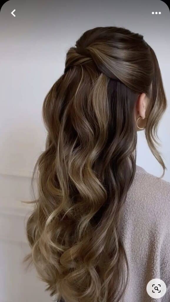 Elegant half-up hairstyle with long, wavy brown hair and subtle golden highlights.