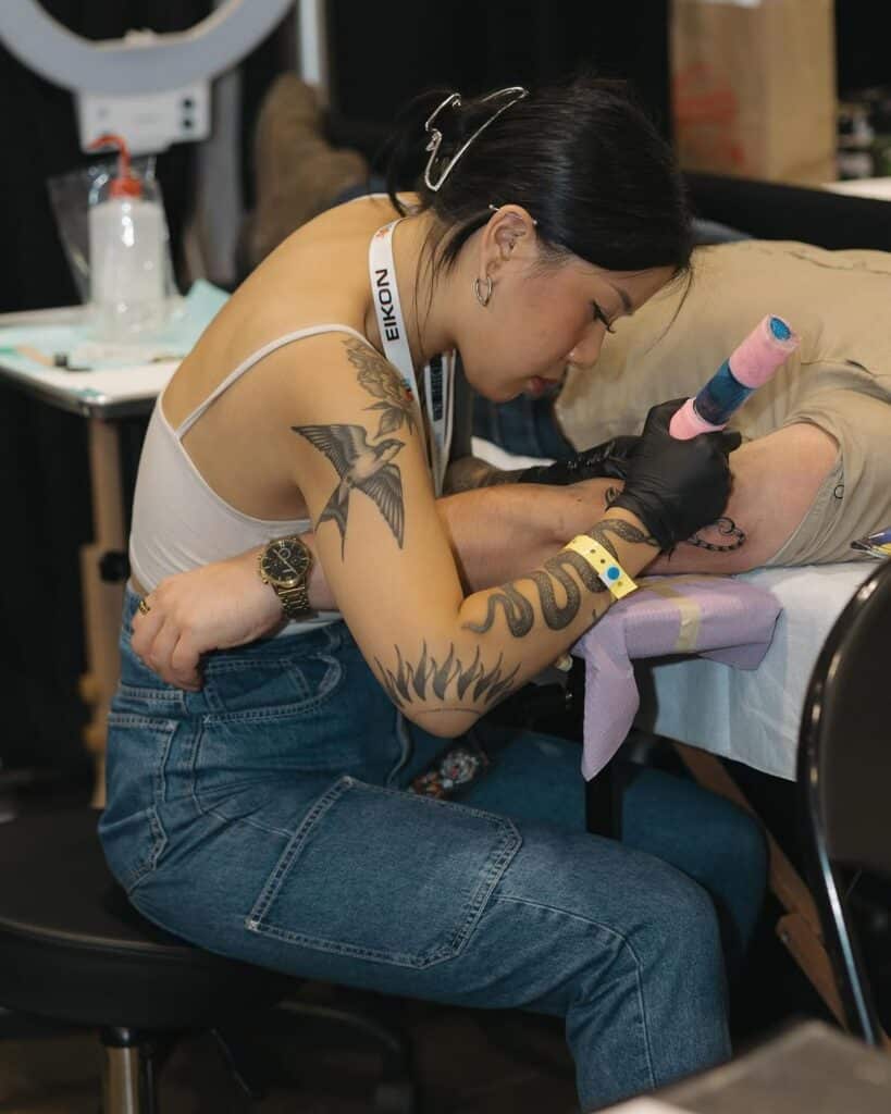 e1293d66d5a67a168ebc2529cd1a21c8 Tattoo artist creating arm design at a convention, showcasing detailed tattooing process and ink artistry. | Sky Rye Design Tattoo artist creating arm design at a convention, showcasing detailed tattooing process and ink artistry.