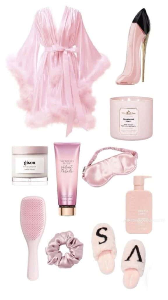 Collection of pink self-care items including robe, candle, lotion, slippers, brush, mask, and hair tie for a cozy spa day.