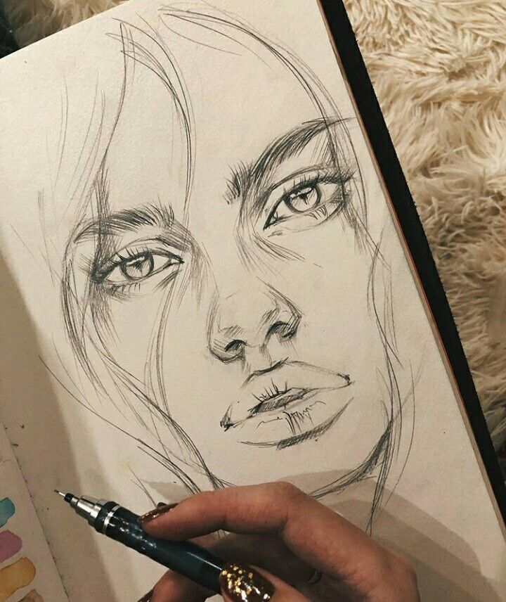 e43d792496e506e8b633082693efa0aa Pencil drawing of a woman's face in a sketchbook, with a hand holding a pen nearby. | Sky Rye Design Pencil drawing of a woman's face in a sketchbook, with a hand holding a pen nearby.
