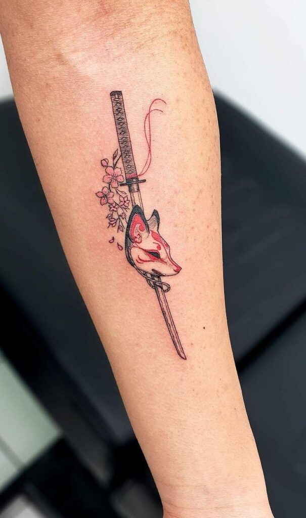 e926d56b-f89c-4a1d-85d2-3f8f96e71852 Fox mask and katana tattoo with cherry blossoms on forearm. | Sky Rye Design Fox mask and katana tattoo with cherry blossoms on forearm.