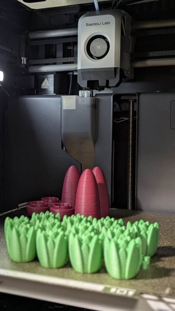 edf2979be5c0492dacf73d51dc3c9ca9 3D printer creating colorful plastic tulip shapes in a workshop setting. | Sky Rye Design 3D printer creating colorful plastic tulip shapes in a workshop setting.