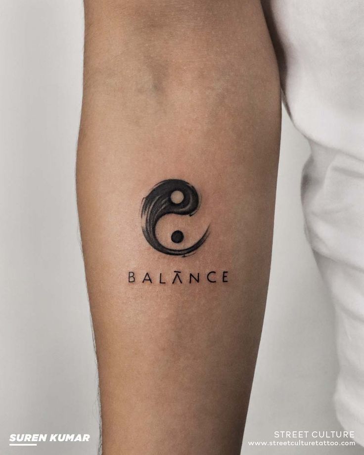 ee18777b-fc41-4544-a4b9-08d5b222d058 Arm tattoo with a stylized yin-yang symbol and the word balance, featuring intricate black ink design. | Sky Rye Design Arm tattoo with a stylized yin-yang symbol and the word balance, featuring intricate black ink design.