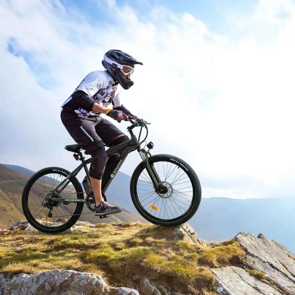 ef2909840e65e8fef88e20dc209ce066_6ab28f26-96e9-4416-8652-d8ad83b195dd_5000x Mountain biker on rocky trail, wearing helmet and gear, rides an electric bike against a scenic mountain backdrop. | Sky Rye Design Mountain biker on rocky trail, wearing helmet and gear, rides an electric bike against a scenic mountain backdrop.