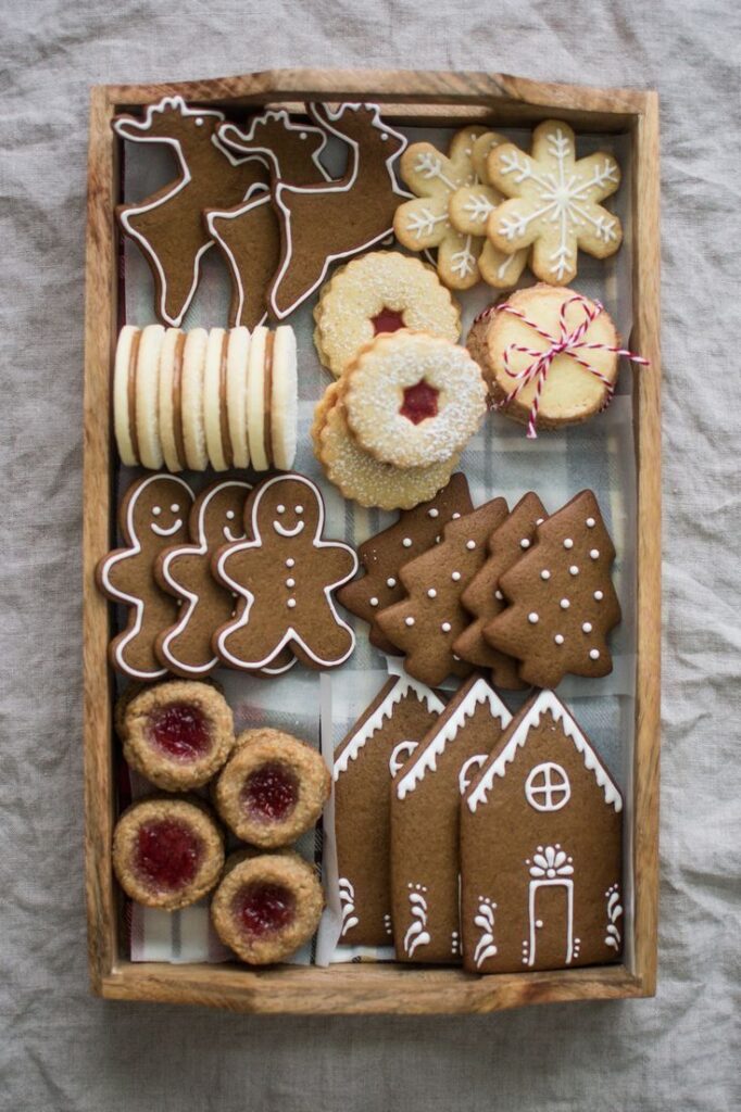 Assorted festive cookies including gingerbread shapes and jam-filled treats in a wooden box, perfect for holiday celebrations.