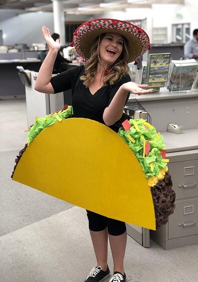 Person in taco costume with sombrero smiling in office setting. Fun, festive outfit for themed event.