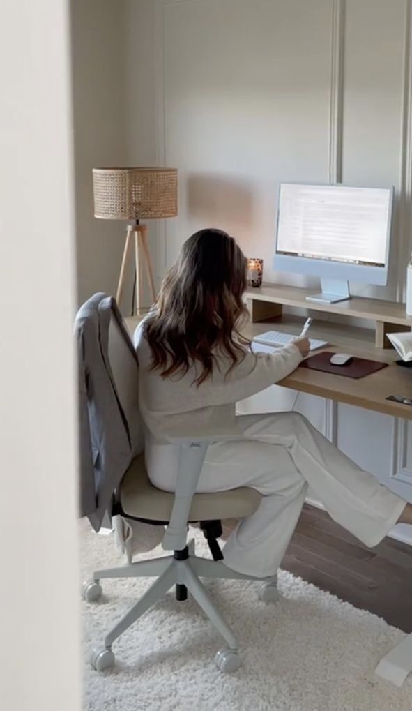 f91181bb-a5e7-41d0-8721-e2f413d99d38 Woman working at a desk with a computer and notepad in a cozy home office setup. | Sky Rye Design Woman working at a desk with a computer and notepad in a cozy home office setup.