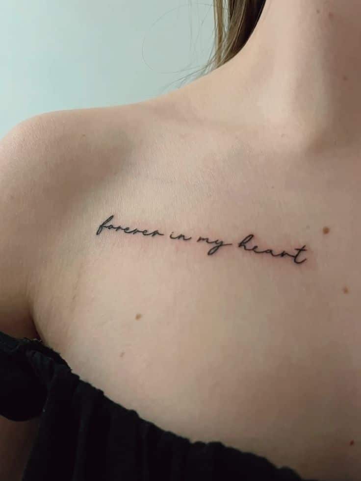f9193e660d2fb417f2f7078e1de556f4 Close-up of a cursive forever in my heart tattoo on a person's collarbone, symbolizing memory or love. | Sky Rye Design Close-up of a cursive forever in my heart tattoo on a person's collarbone, symbolizing memory or love.