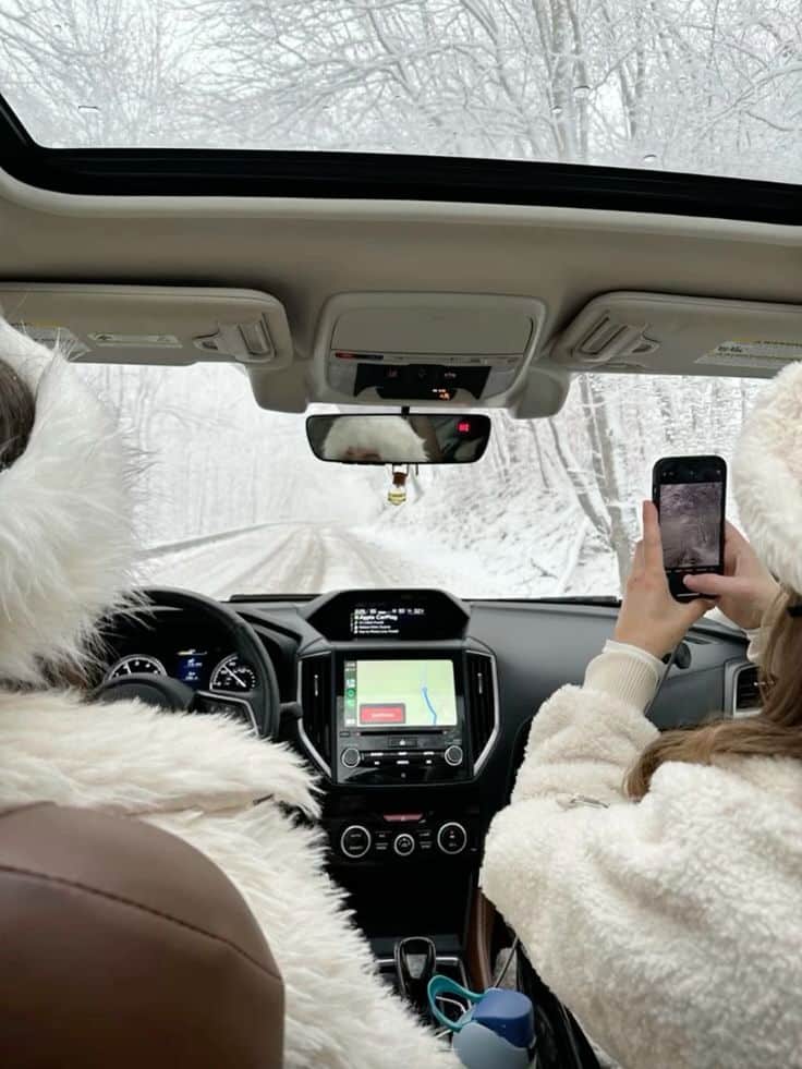 fb77dda7-18db-4881-960b-05a898dd6ca1 Driving through a snowy forest, two people in white coats capture the winter scene from inside a car. | Sky Rye Design Driving through a snowy forest, two people in white coats capture the winter scene from inside a car.