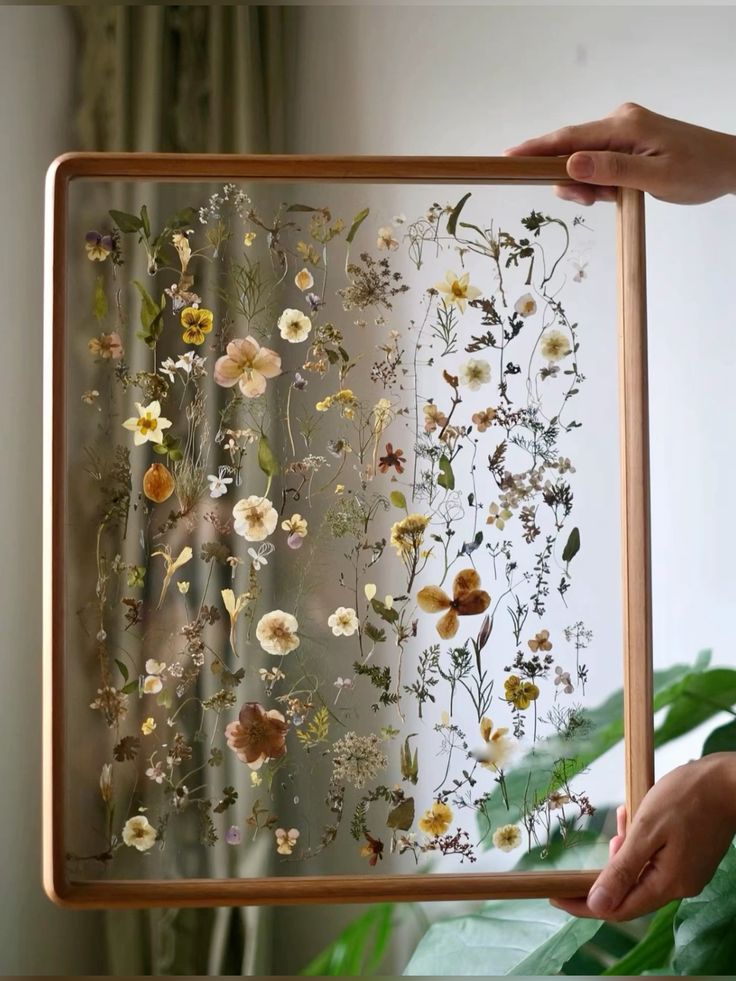 flower art Framed pressed flowers in a wooden frame, held up by hands with a light-filled background. | Sky Rye Design Framed pressed flowers in a wooden frame, held up by hands with a light-filled background.