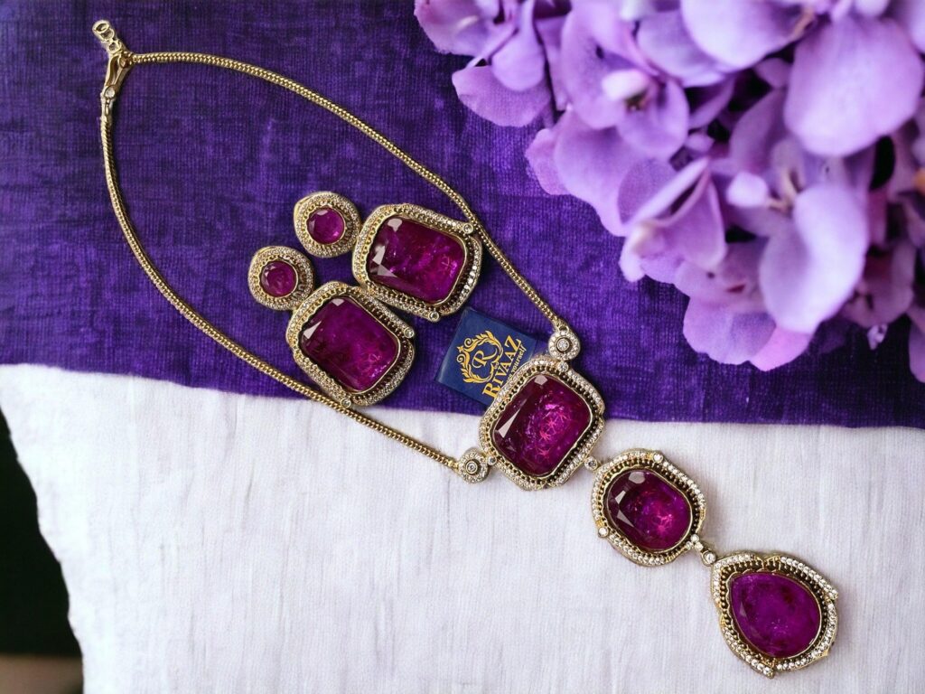 Elegant purple gemstone necklace with gold accents on a purple fabric, adorned with hydrangea flowers.
