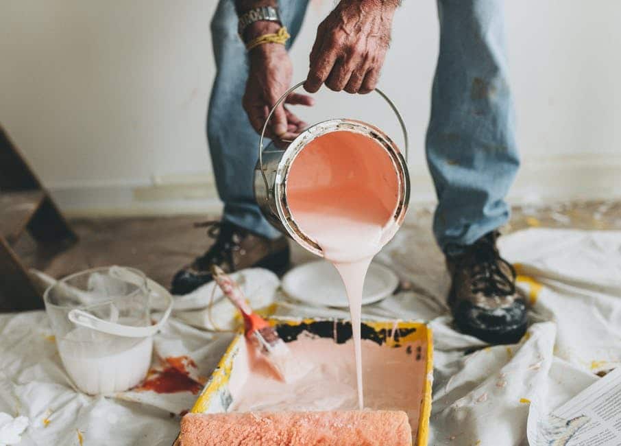 image Person pouring pink paint into a tray, preparing for a home renovation or DIY project. | Sky Rye Design Person pouring pink paint into a tray, preparing for a home renovation or DIY project.