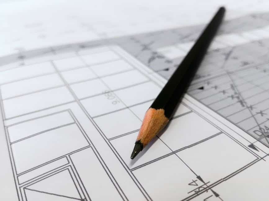image Black pencil resting on architectural blueprint with precise drawings and grid layout. | Sky Rye Design Black pencil resting on architectural blueprint with precise drawings and grid layout.