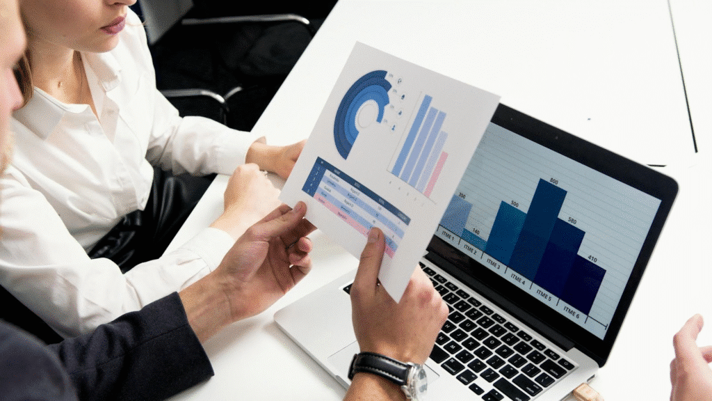 Professionals analyzing business charts on a laptop and paper during a meeting.