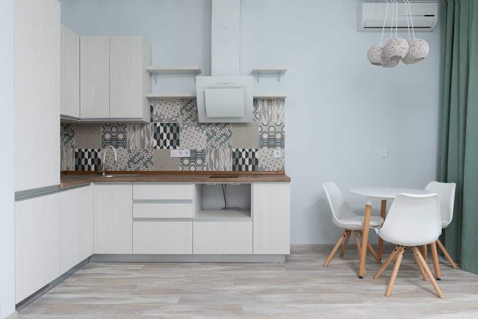 image Modern kitchen with white cabinets, patterned backsplash, round table, and chairs against a light wood floor. | Sky Rye Design Modern kitchen with white cabinets, patterned backsplash, round table, and chairs against a light wood floor.