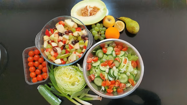 image Fresh fruit and vegetable salad assortment with melon, grapes, tomatoes, cucumber, lettuce, and mixed fruit bowl on a table. | Sky Rye Design Fresh fruit and vegetable salad assortment with melon, grapes, tomatoes, cucumber, lettuce, and mixed fruit bowl on a table.