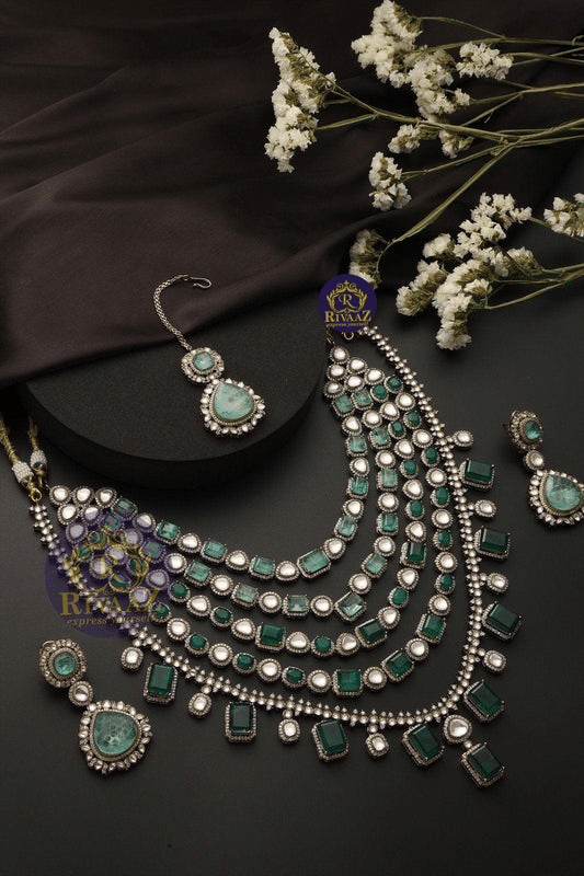 Elegant green and silver jewelry set with necklace, earrings, and floral accents on a dark background.