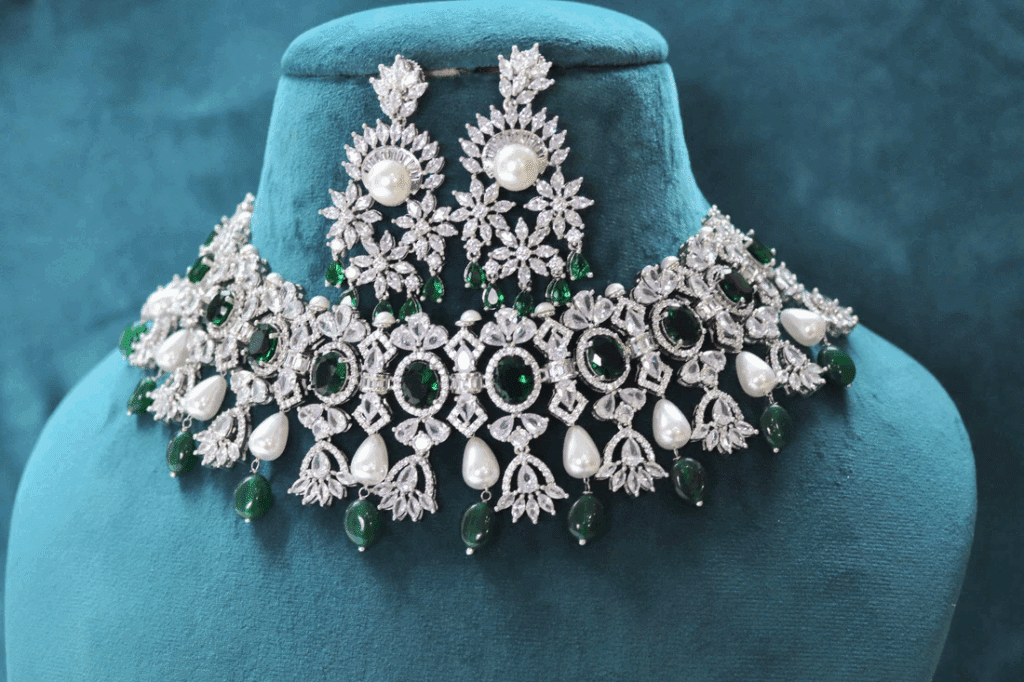 Elegant diamond and emerald necklace with matching earrings on a display stand.