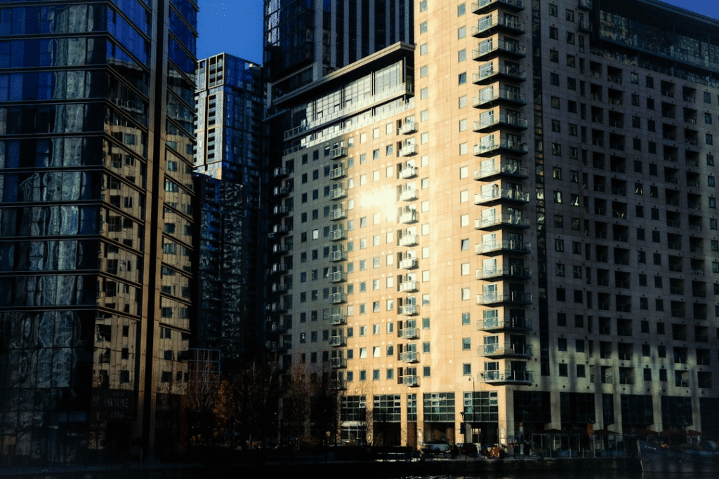 Modern high-rise buildings in sunlight, reflecting glass windows, urban cityscape architecture.