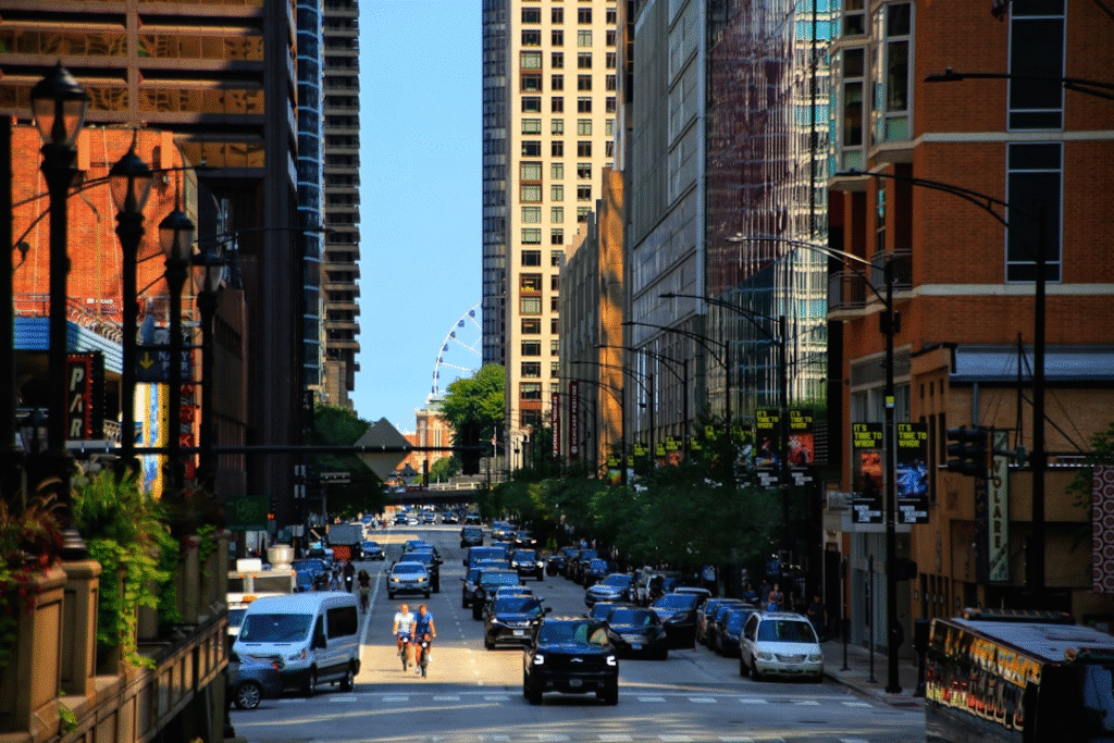 Bustling city street with traffic, cyclists, and skyscrapers; a Ferris wheel visible in the background.