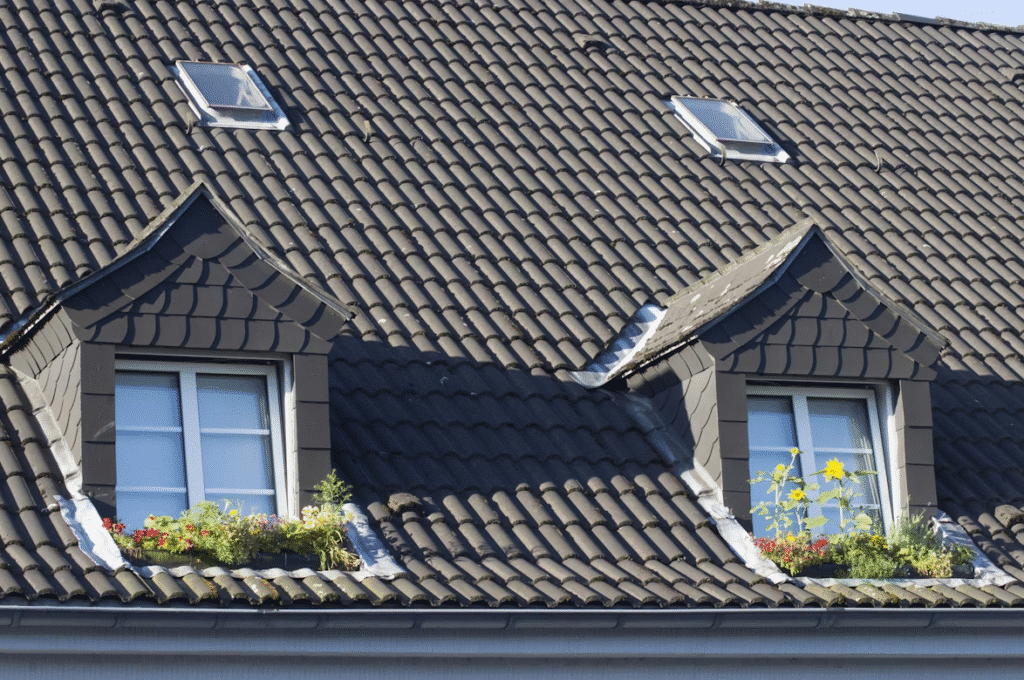 Slate roof with dormer windows and vibrant flower boxes showcasing a charming architectural design.