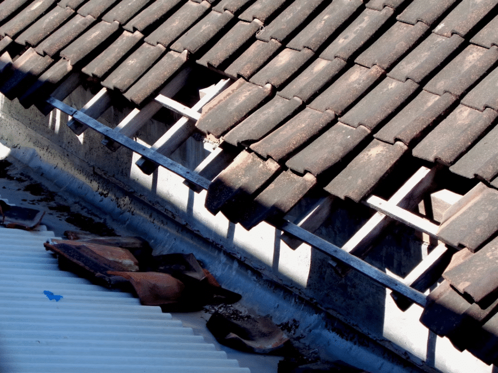 image Damaged roof with missing tiles exposing beams, highlighting need for repair. | Sky Rye Design Damaged roof with missing tiles exposing beams, highlighting need for repair.
