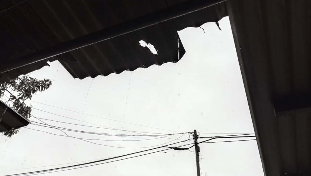 image Damaged roof with holes, leaking rainwater against cloudy sky; power lines in the background. | Sky Rye Design Damaged roof with holes, leaking rainwater against cloudy sky; power lines in the background.