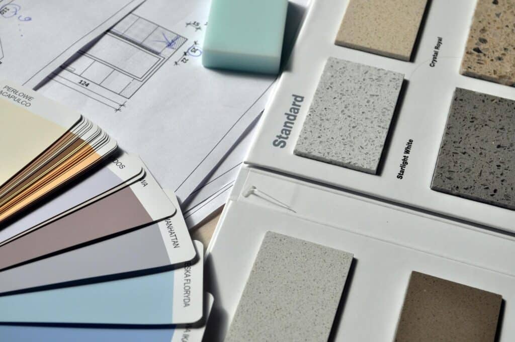 Color swatches and material samples on architectural blueprint for interior design planning.