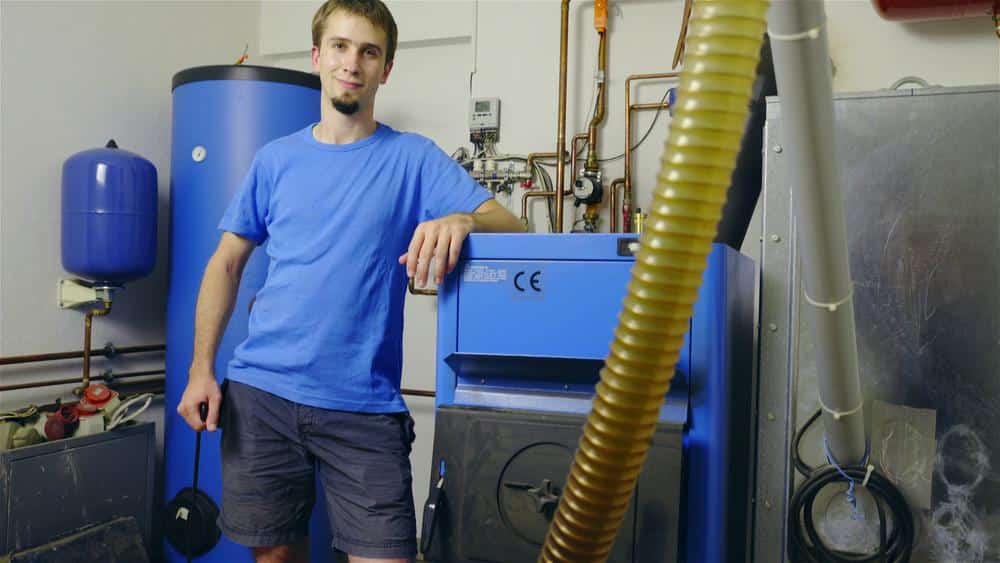 image1 Technician standing by household heating system in utility room. | Sky Rye Design Technician standing by household heating system in utility room.