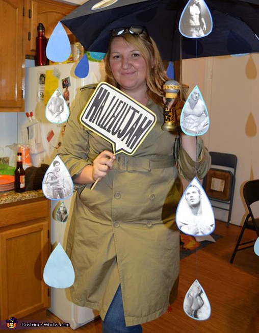 Person in a creative costume holding Hallelujah sign under umbrella with photos, in a kitchen setting.