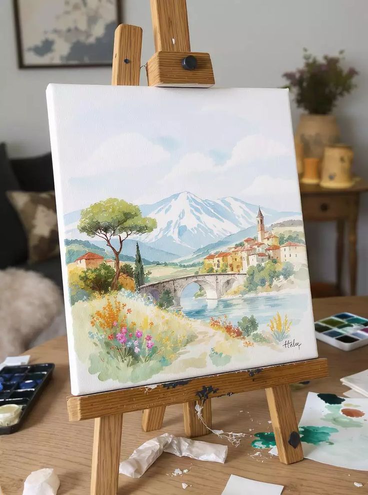 A vibrant landscape painting on an easel, featuring mountains, a bridge, and colorful flowers.