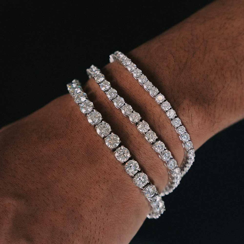 Three elegant diamond tennis bracelets sparkling on a wrist, showcasing luxury and style.