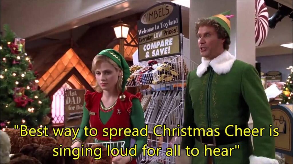 Two people in festive elf costumes stand in a decorated store with a Christmas quote overlay.