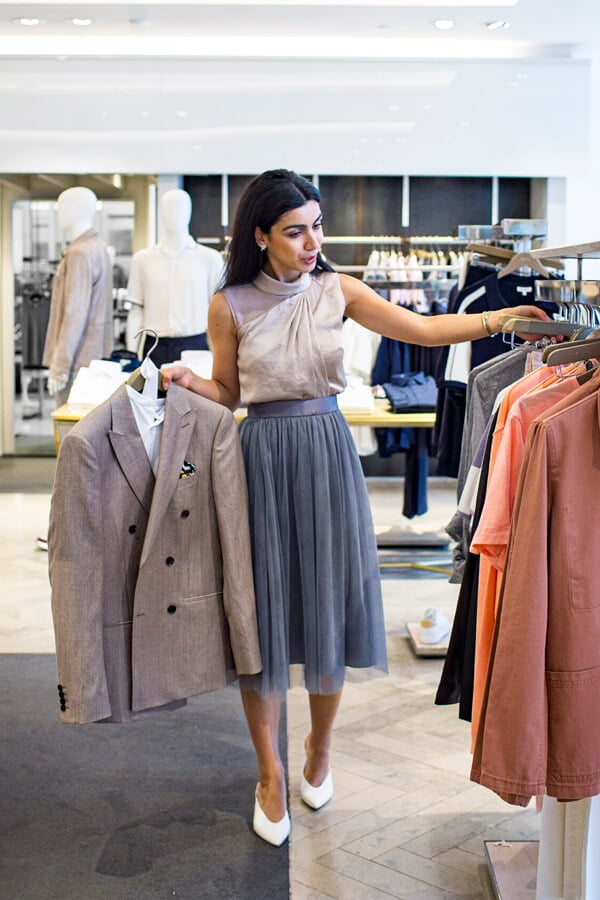 men-personal-stylist-london Woman shopping for stylish suits in a clothing store, holding a beige blazer. | Sky Rye Design Woman shopping for stylish suits in a clothing store, holding a beige blazer.