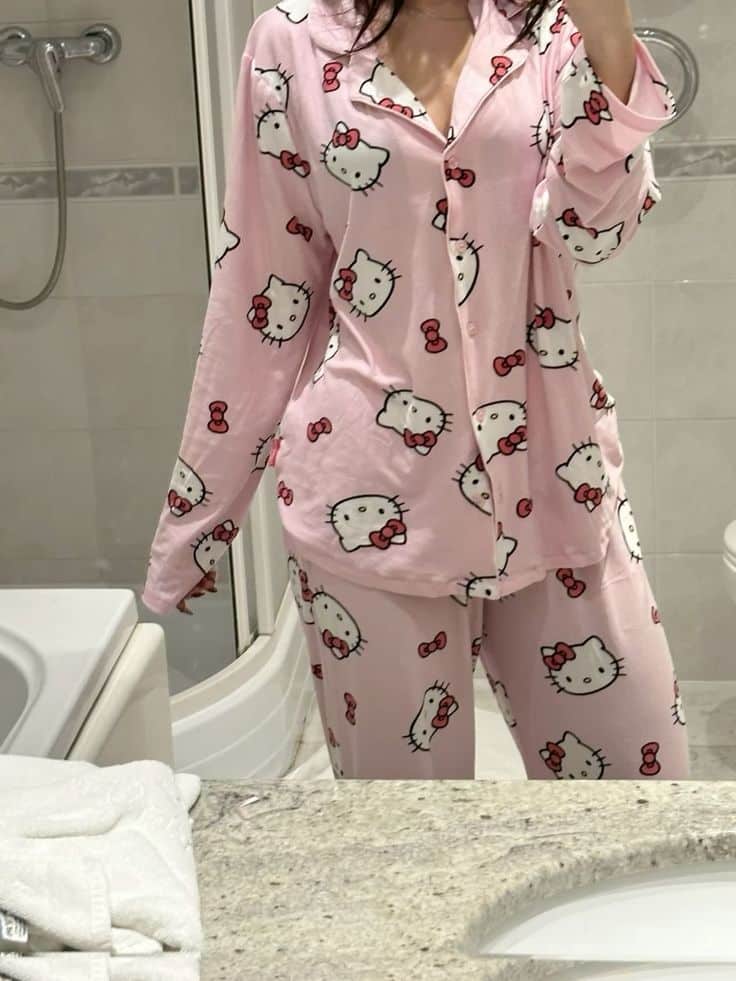 Person in pink Hello Kitty pajamas taking a mirror selfie in a bathroom.
