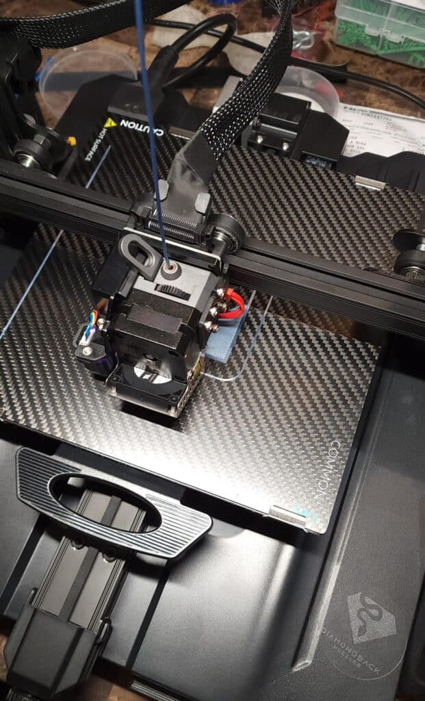 occowr3oadl91 3D printer in action, extruding filament on a carbon fiber build plate. | Sky Rye Design 3D printer in action, extruding filament on a carbon fiber build plate.